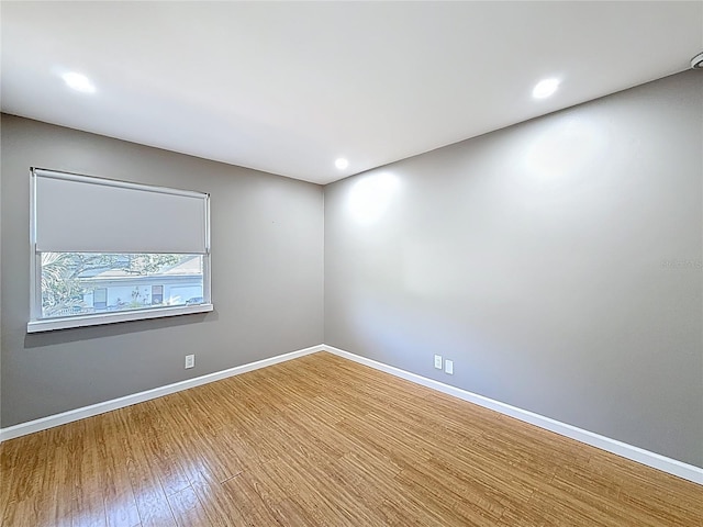 empty room featuring wood finished floors, baseboards, and recessed lighting