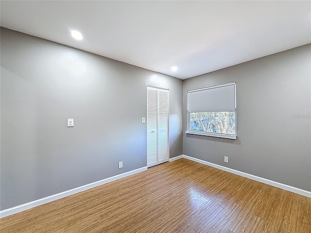 spare room with baseboards, recessed lighting, and wood finished floors