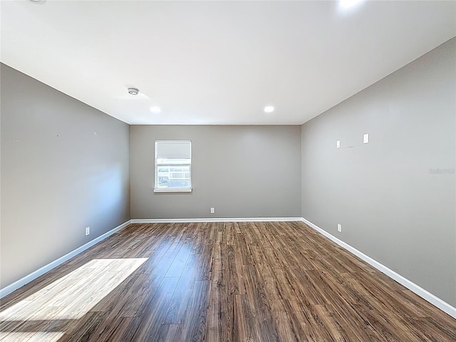 unfurnished room with baseboards and dark wood-type flooring