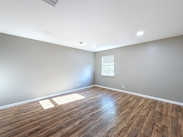 empty room with baseboards, dark wood-style floors, visible vents, and recessed lighting