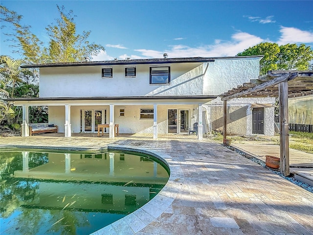 rear view of property with french doors, a patio, an outdoor pool, stucco siding, and a pergola
