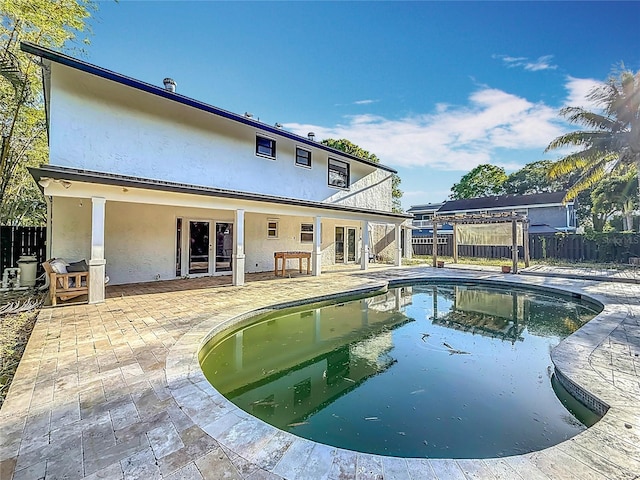 rear view of property with a patio area, fence, french doors, stucco siding, and a fenced in pool