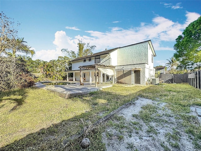 back of property with central AC, a wooden deck, a fenced backyard, and a lawn