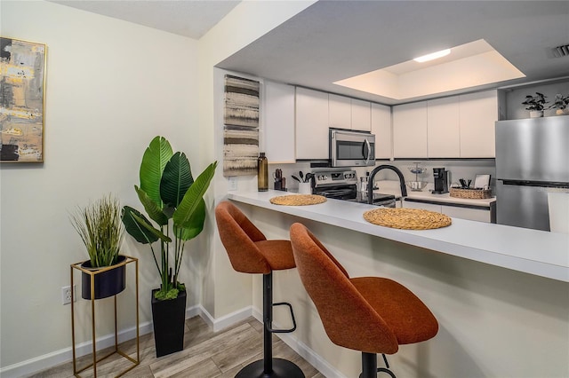kitchen featuring appliances with stainless steel finishes, a breakfast bar area, and white cabinets