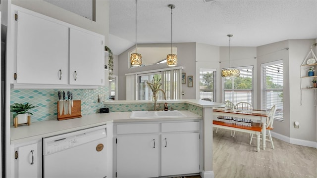 kitchen with white dishwasher, a sink, light countertops, tasteful backsplash, and a textured ceiling