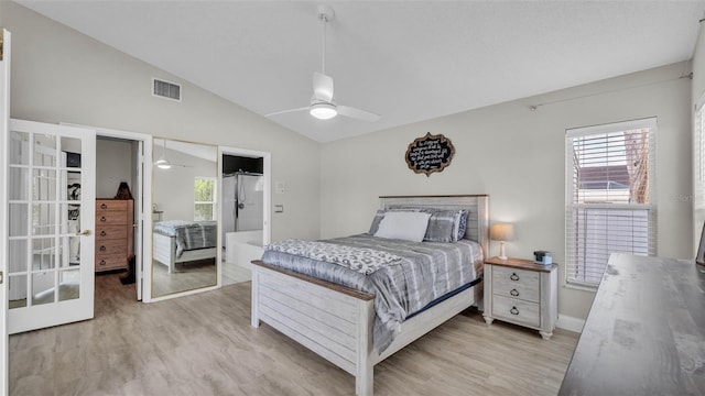 bedroom featuring vaulted ceiling, light wood-style flooring, multiple windows, and french doors