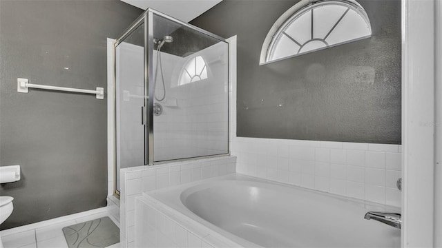 full bathroom with a shower stall, a bath, baseboards, and toilet