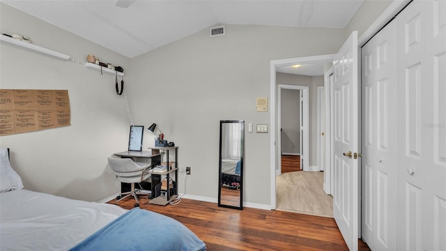 bedroom with wood finished floors, a closet, vaulted ceiling, baseboards, and a ceiling fan