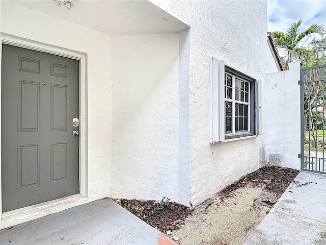10764 Lenox Rd, Hollywood, FL 33026 - view of exterior entry with stucco siding and a gate