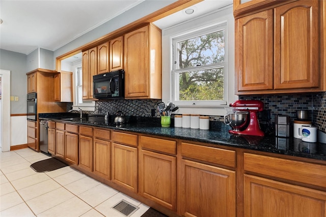716 S Franklin Pl, Lakeland, FL 33815 - kitchen with black appliances, light tile patterned floors, dark stone countertops, decorative backsplash, and brown cabinets