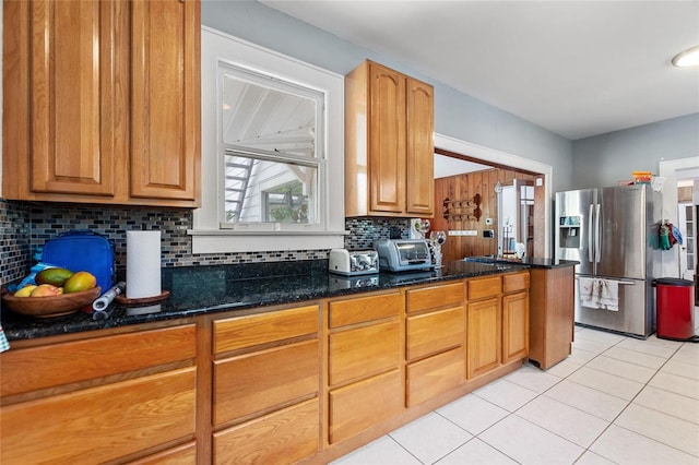 716 S Franklin Pl, Lakeland, FL 33815 - kitchen with stainless steel refrigerator with ice dispenser, light tile patterned floors, decorative backsplash, dark stone countertops, and brown cabinets