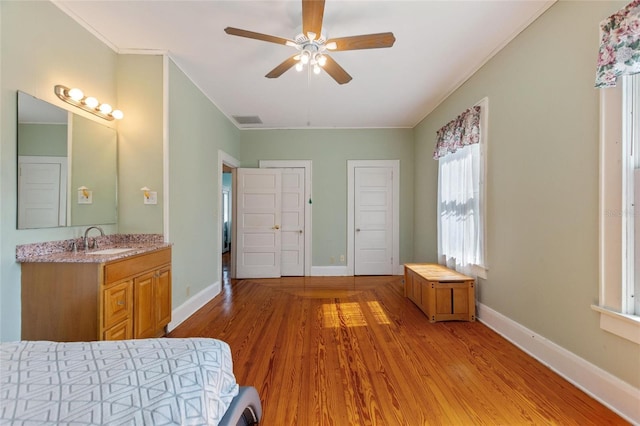 716 S Franklin Pl, Lakeland, FL 33815 - bedroom featuring a sink, light wood finished floors, ornamental molding, baseboards, and two closets