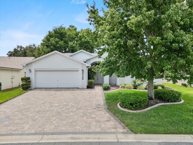 6086 Swallow Dr, Lakeland, FL 33809 - view of front of property with decorative driveway, an attached garage, stucco siding, and a front lawn