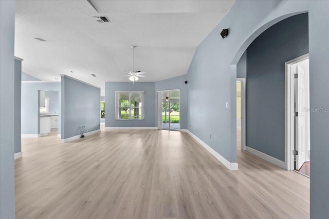 6086 Swallow Dr, Lakeland, FL 33809 - unfurnished living room with a ceiling fan, lofted ceiling, light wood-style flooring, arched walkways, and baseboards
