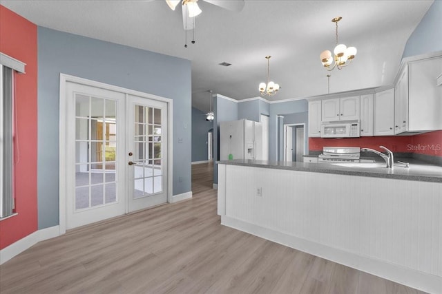 6086 Swallow Dr, Lakeland, FL 33809 - kitchen with white appliances, a chandelier, a ceiling fan, dark countertops, and light wood-type flooring