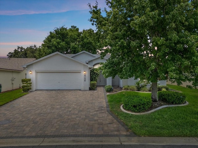 6086 Swallow Dr, Lakeland, FL 33809 - view of front of home featuring an attached garage, decorative driveway, a front lawn, and stucco siding