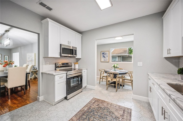 kitchen featuring stainless steel appliances, tasteful backsplash, baseboards, light stone counters, and white cabinetry