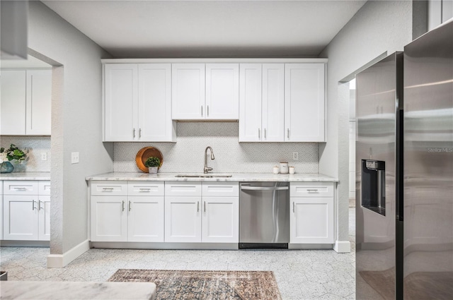 kitchen featuring stainless steel appliances, a sink, tasteful backsplash, baseboards, and light stone counters