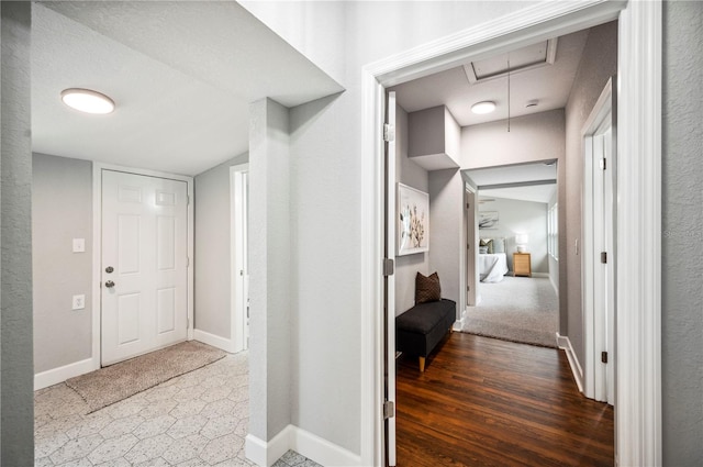 hall featuring attic access and baseboards