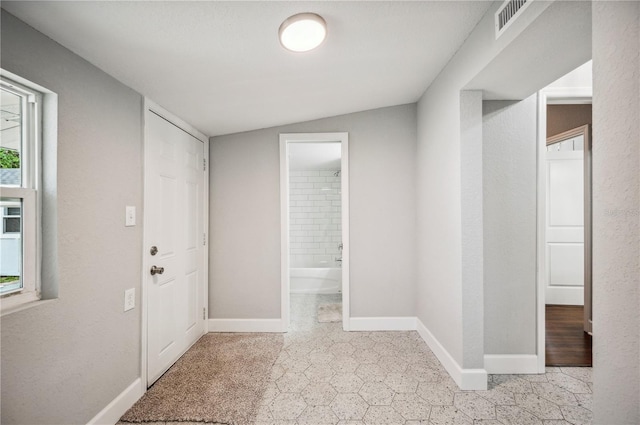 corridor featuring baseboards and vaulted ceiling