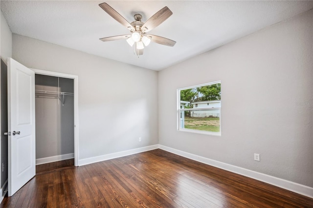 unfurnished bedroom with dark wood-style flooring, baseboards, a closet, and a ceiling fan