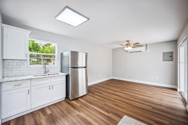 kitchen featuring freestanding refrigerator, a sink, an AC wall unit, dark wood-style flooring, and ceiling fan