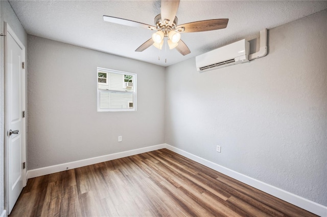 unfurnished bedroom featuring a wall mounted air conditioner, wood finished floors, baseboards, and ceiling fan