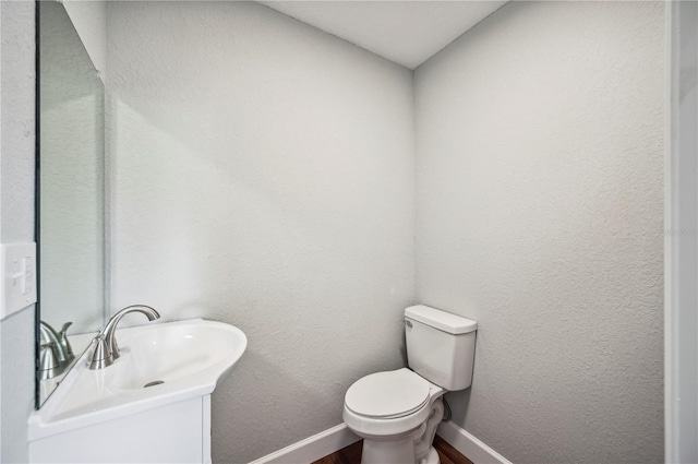 bathroom featuring baseboards, wood finished floors, and toilet