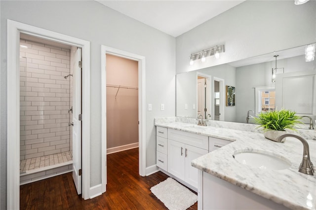 full bathroom with wood finished floors, a shower stall, vanity, baseboards, and a walk in closet