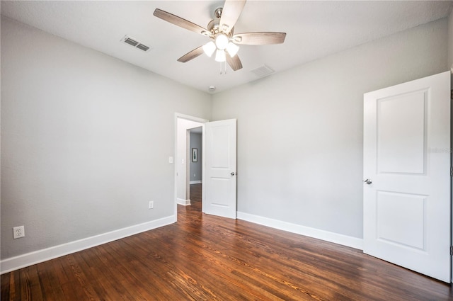 spare room with a ceiling fan, dark wood-type flooring, and baseboards