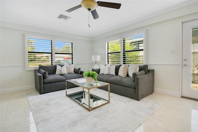 living room with tile patterned floors, crown molding, plenty of natural light, a ceiling fan, and baseboards