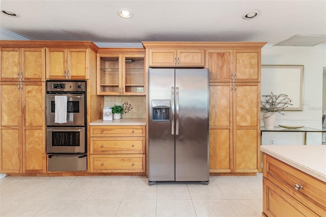 kitchen featuring stainless steel appliances, a warming drawer, light countertops, glass insert cabinets, and brown cabinetry