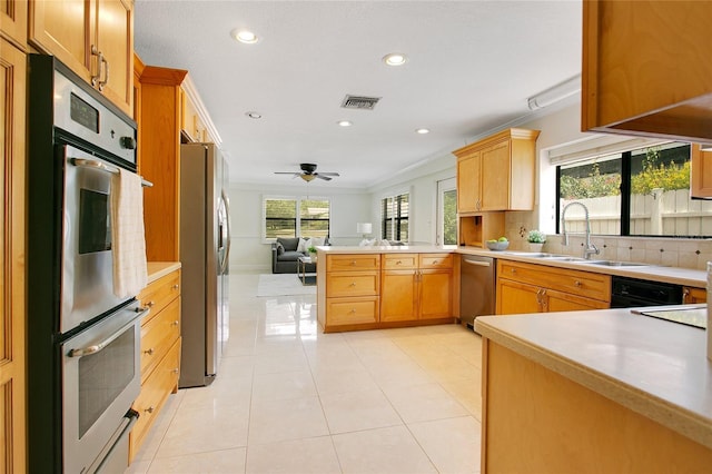kitchen with stainless steel appliances, a sink, open floor plan, a peninsula, and light countertops