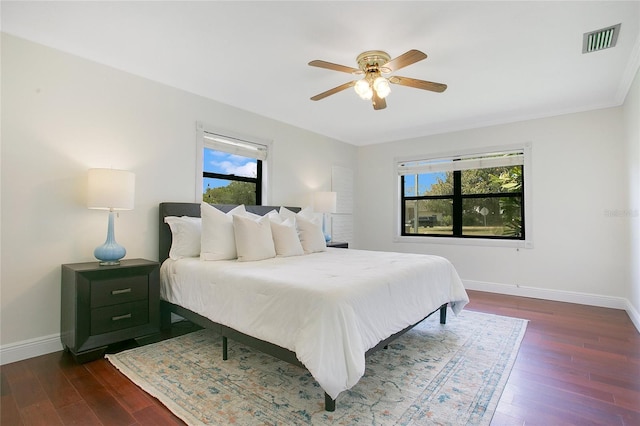 bedroom featuring dark wood finished floors, multiple windows, baseboards, and a ceiling fan