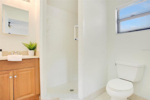 full bath with a tile shower, toilet, vanity, ceiling fan, and baseboards