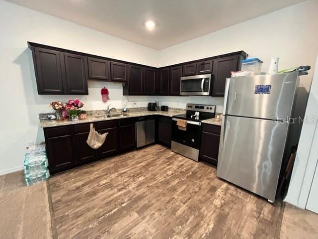 879 Grandin St, Davenport, FL 33837 - kitchen featuring stainless steel appliances, a sink, wood finished floors, and light stone countertops