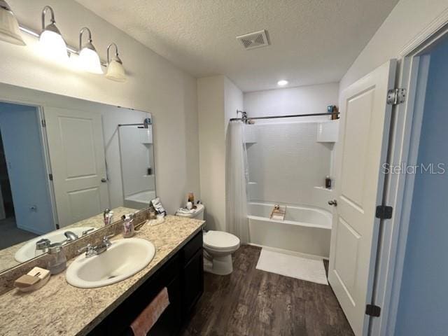 879 Grandin St, Davenport, FL 33837 - bathroom featuring toilet, wood finished floors, a textured ceiling, vanity, and shower / bath combo