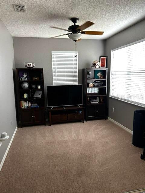 office with a ceiling fan, light colored carpet, a textured ceiling, and baseboards