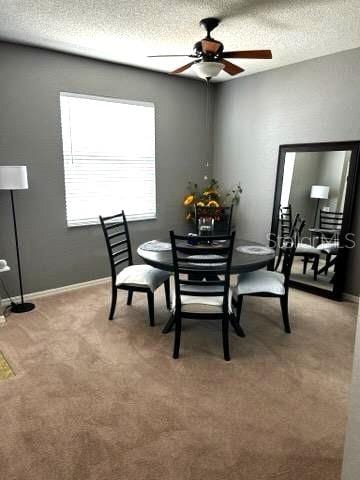 dining room with light carpet, ceiling fan, a textured ceiling, and baseboards