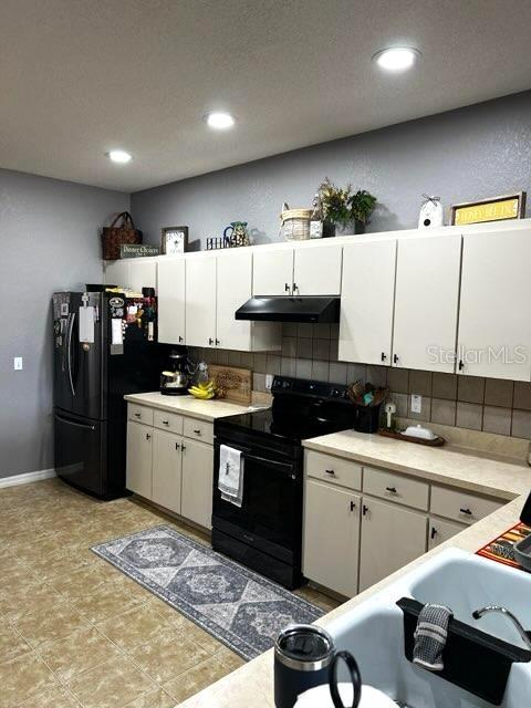 kitchen with black appliances, under cabinet range hood, decorative backsplash, white cabinetry, and recessed lighting