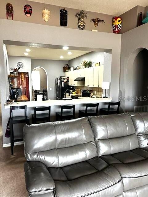 living area with arched walkways and light carpet