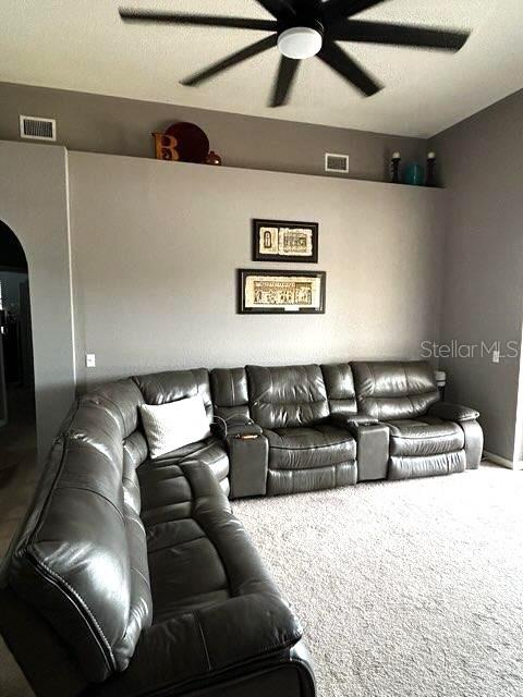 living room with a ceiling fan, arched walkways, and carpet