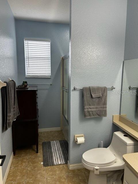 full bathroom with toilet, enclosed tub / shower combo, tile patterned flooring, and vanity