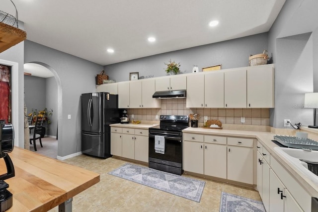 4041 Byrds Crossing Dr, Lakeland, FL 33812 - kitchen with black appliances, under cabinet range hood, arched walkways, light countertops, and backsplash