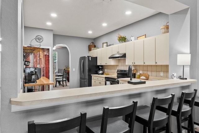 4041 Byrds Crossing Dr, Lakeland, FL 33812 - kitchen featuring stainless steel appliances, under cabinet range hood, decorative backsplash, arched walkways, and recessed lighting