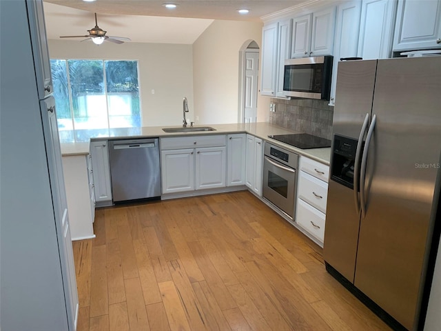 kitchen featuring appliances with stainless steel finishes, a sink, arched walkways, ceiling fan, and white cabinetry