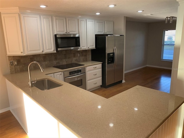 kitchen featuring stainless steel appliances, a sink, baseboards, light wood-type flooring, and backsplash