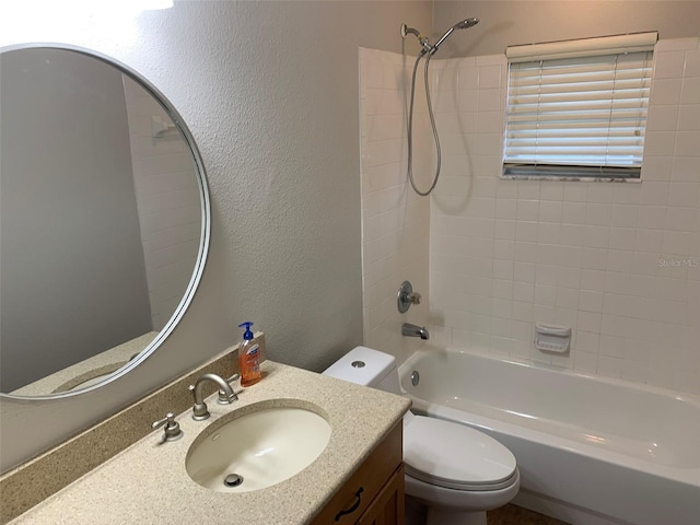 bathroom featuring toilet, shower / bath combination, vanity, and a textured wall