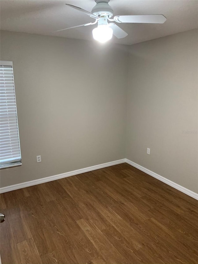 empty room featuring dark wood-style flooring, a ceiling fan, and baseboards