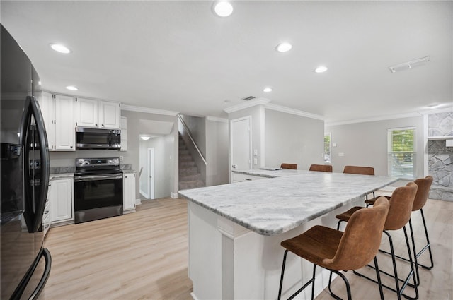 707 Laurel Pointe Ct, Lakeland, FL 33813 - kitchen with electric range, black fridge with ice dispenser, ornamental molding, light wood finished floors, and a kitchen breakfast bar